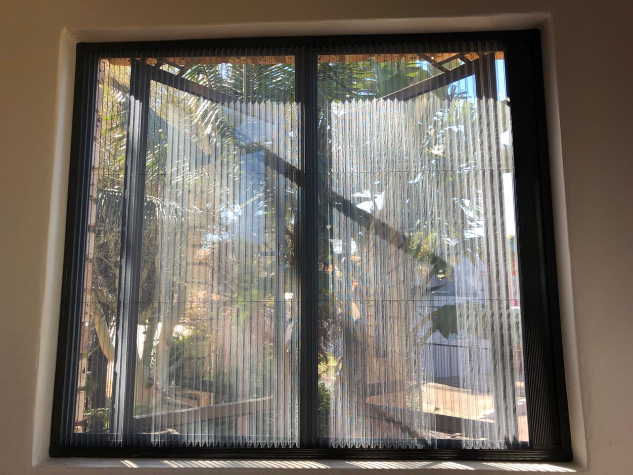 A wide glass doorway fitted with a custom pleated flyscreen