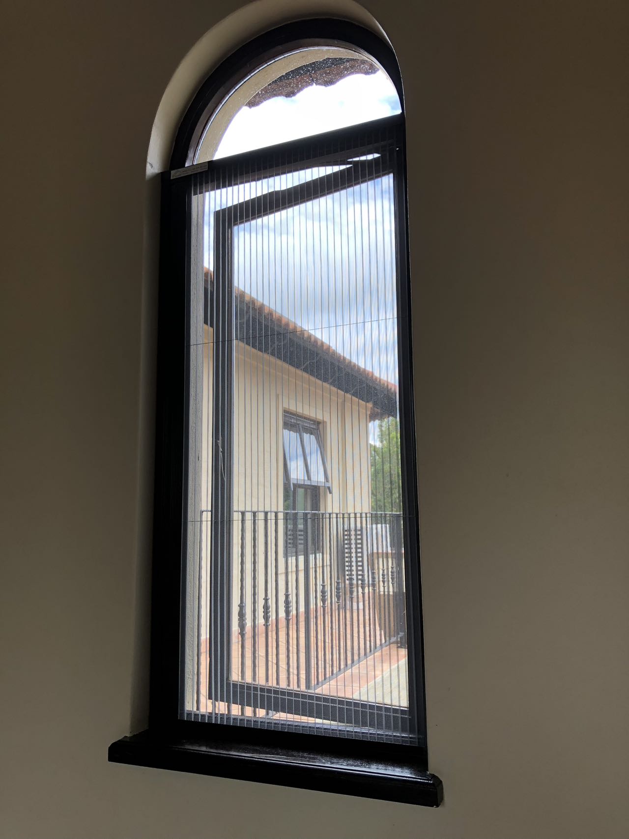 Custom pleated flyscreen fitted to an arched window